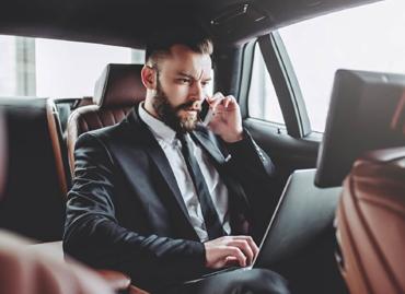 Business traveller working in the back of a car